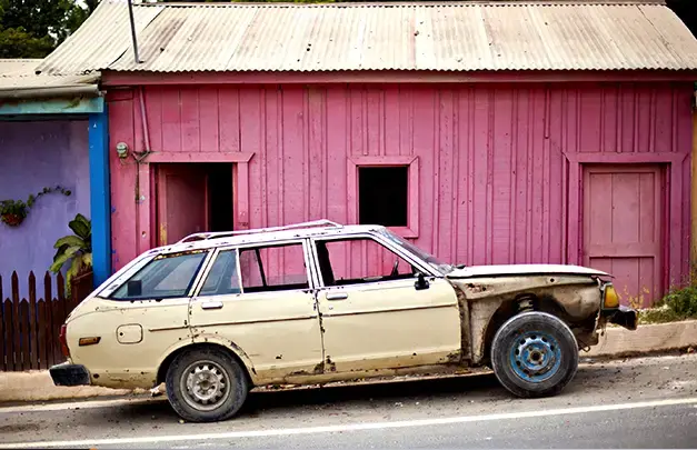 An old car in front of a pink house