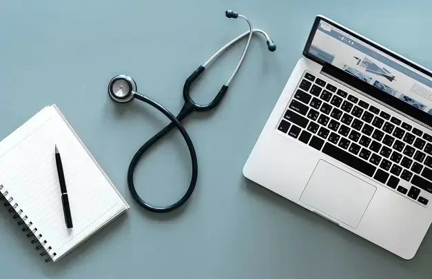 A notebook, stethoscope, and laptop