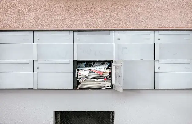 Newspapers overflowing out of a PO box